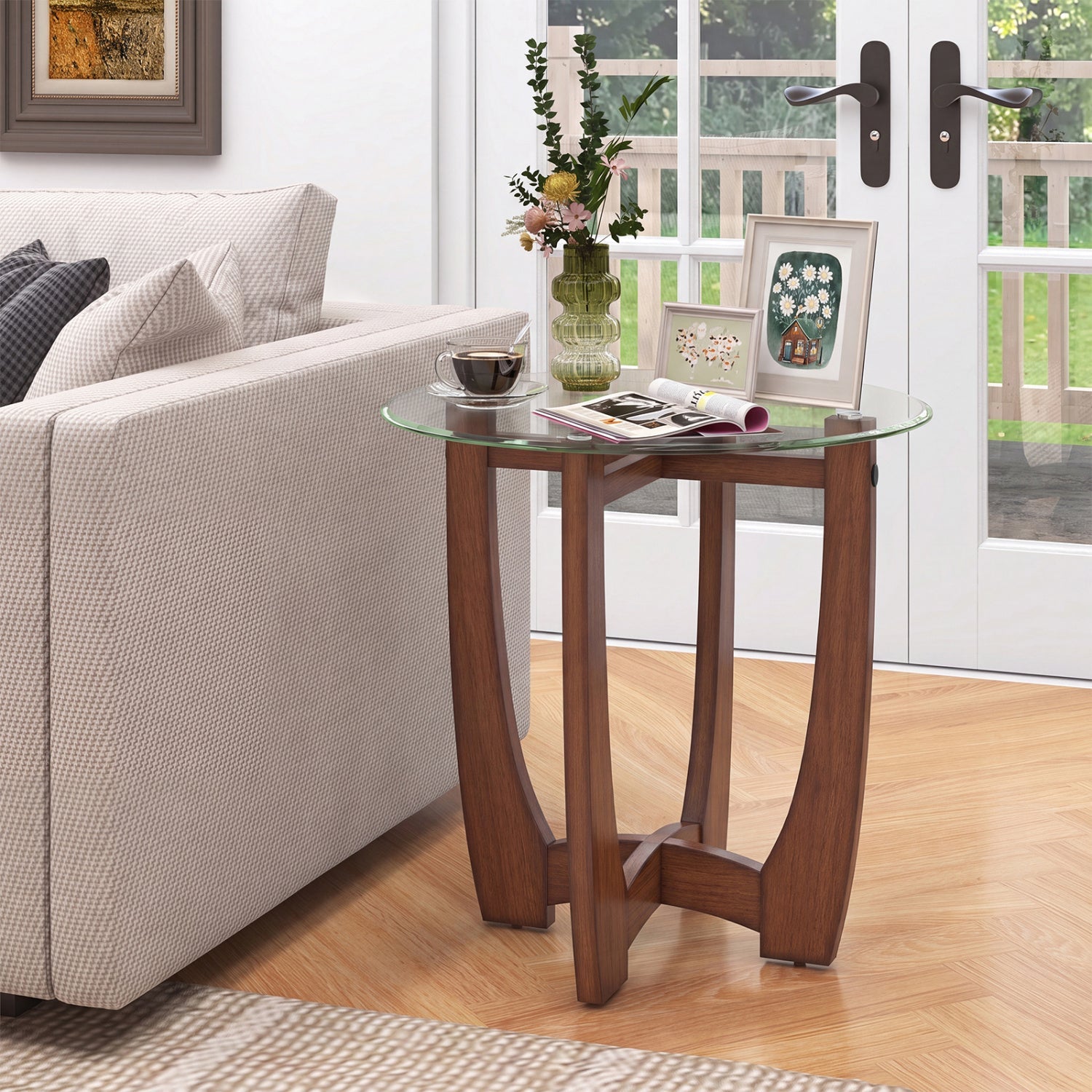 A round glass-top end table with a medium brown wooden frame and curved legs, styled in a bright living room