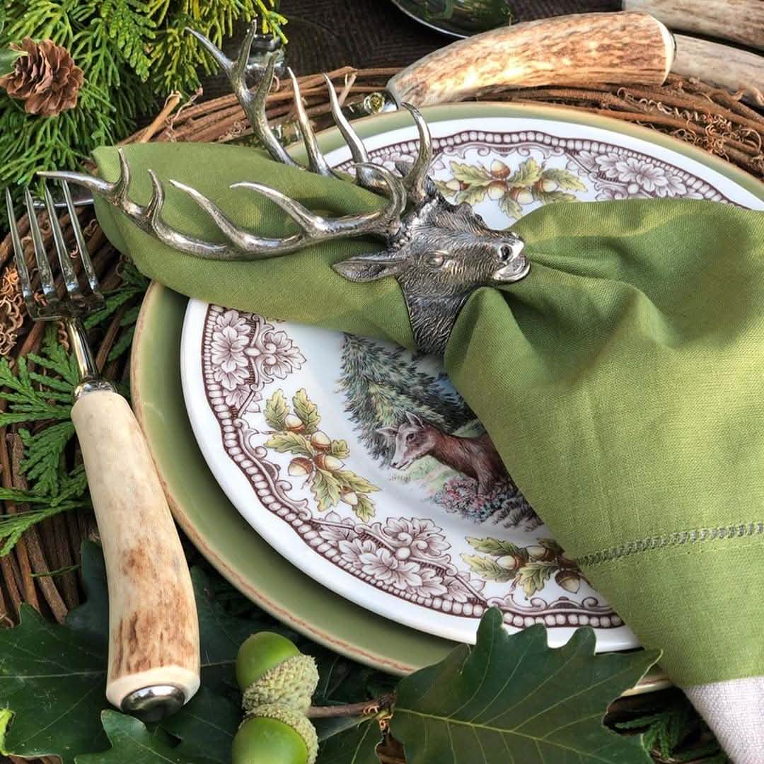 elk napkin ring with cloth napkin at rustic lodge tablescape with deer antler and stag horn accessories