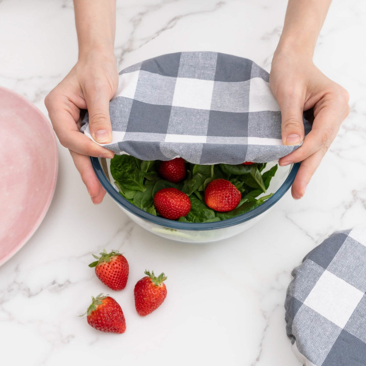putting a reusable cloth bowl cover on a bowl of strawberry salad