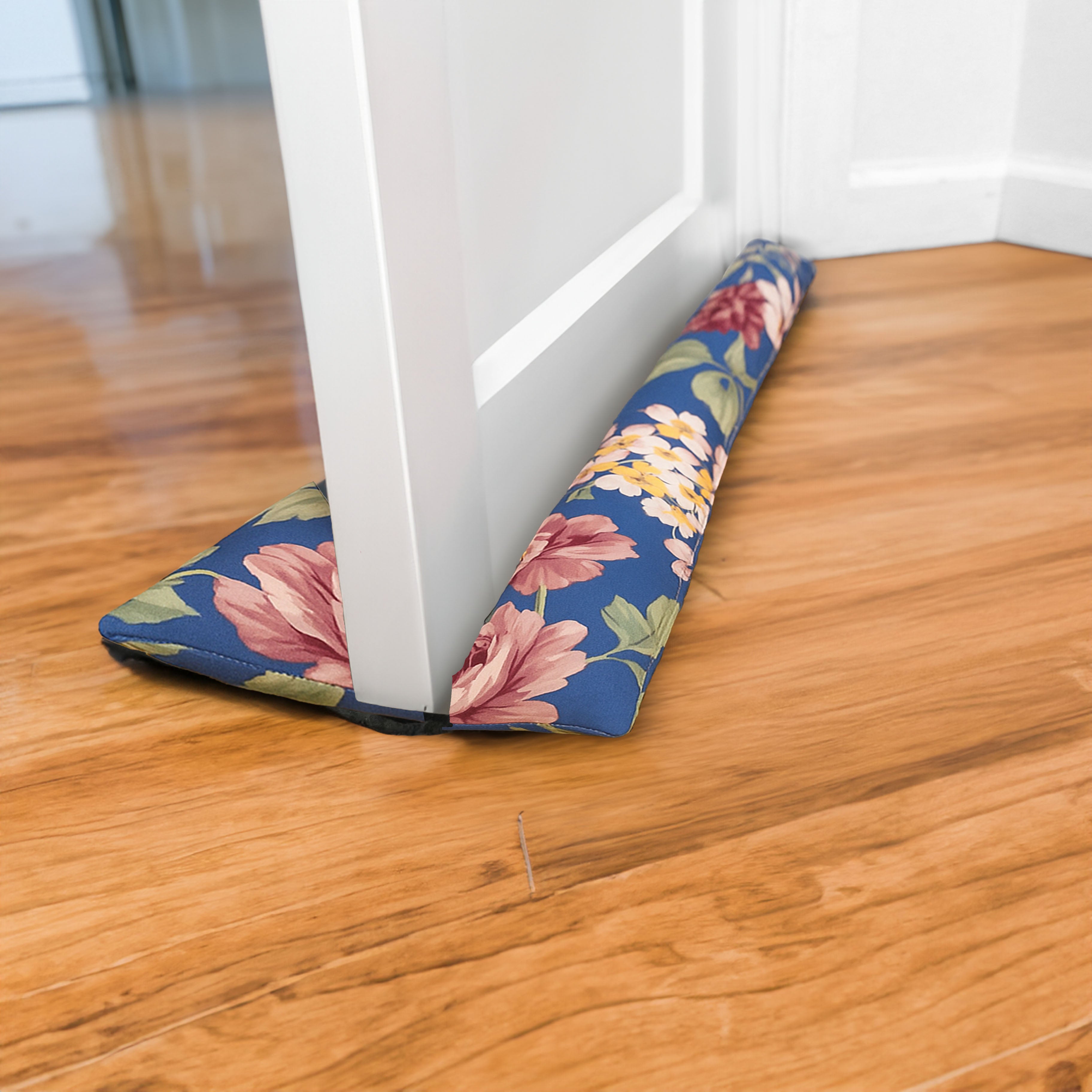 Floral-patterned door draft stopper on a wooden floor