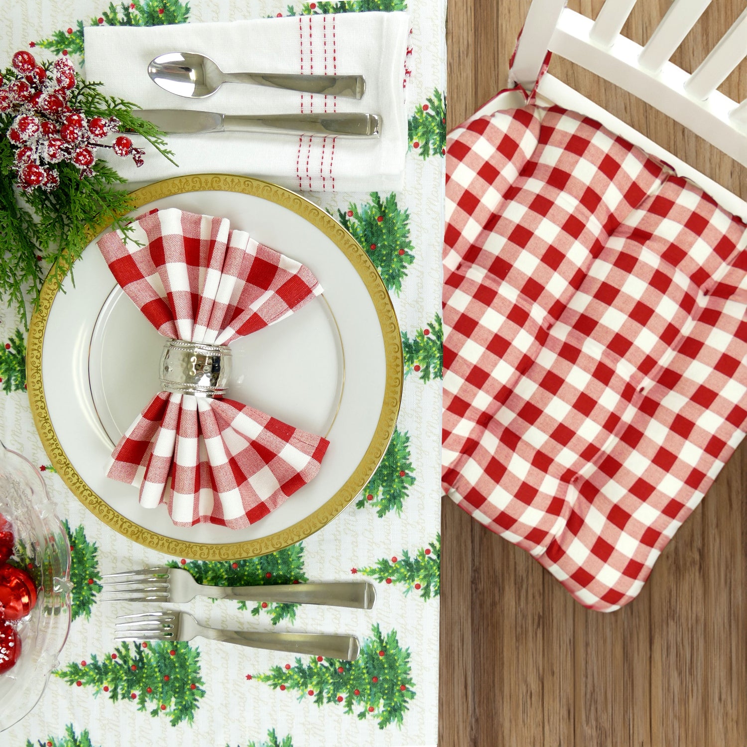 Christmas-themed table setting with red and white checkered chair cushion, gold-rimmed plate, and matching cloth napkins.