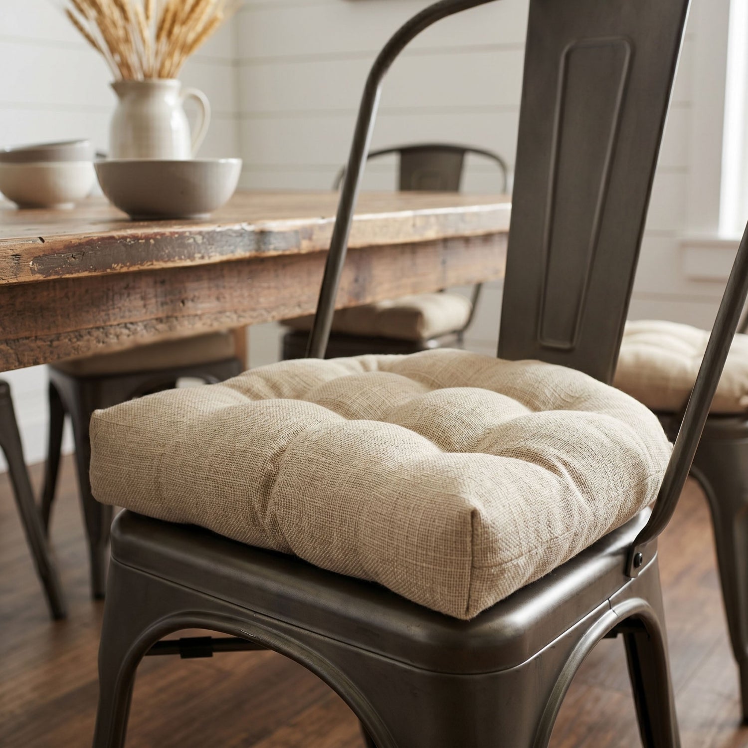 Beige cushion on a metal chair with a wooden table and decor in the background
