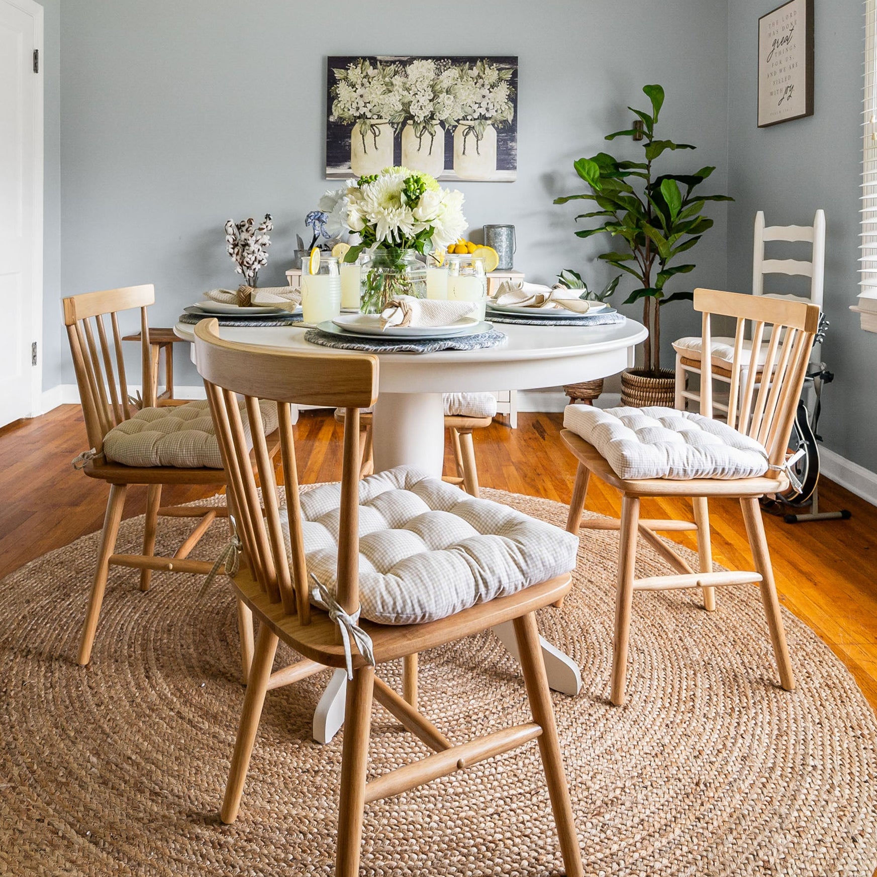 beige gingham dining chair cushions on wooden dining chairs around a white dining room table with a jute rug and farmhouse decor