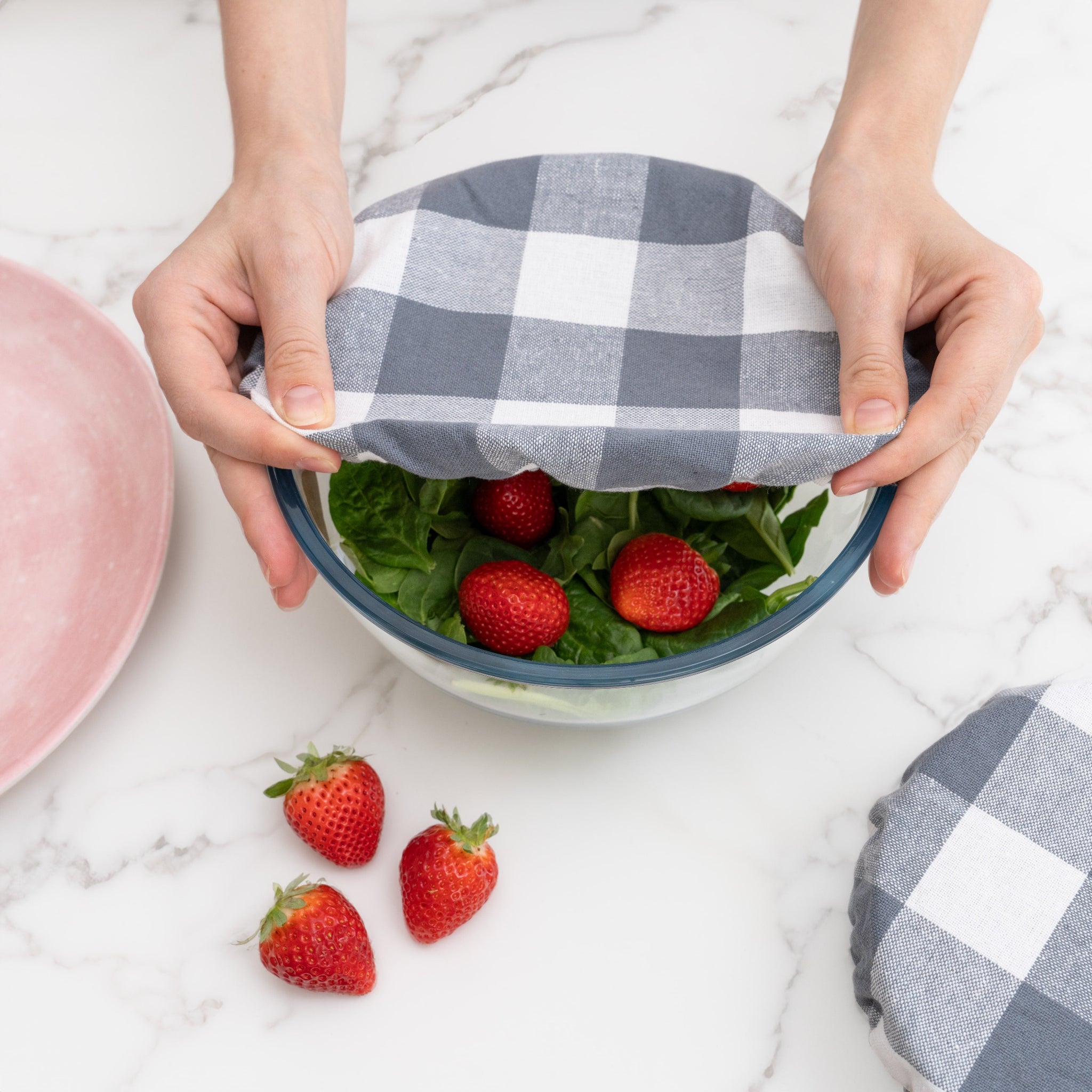 putting a reusable cloth bowl cover on a bowl of strawberry salad