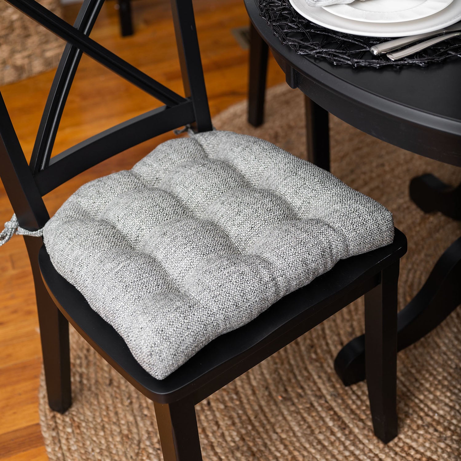 grey upholstered dining chair cushion at black dining room set for dinner party with silver place settings