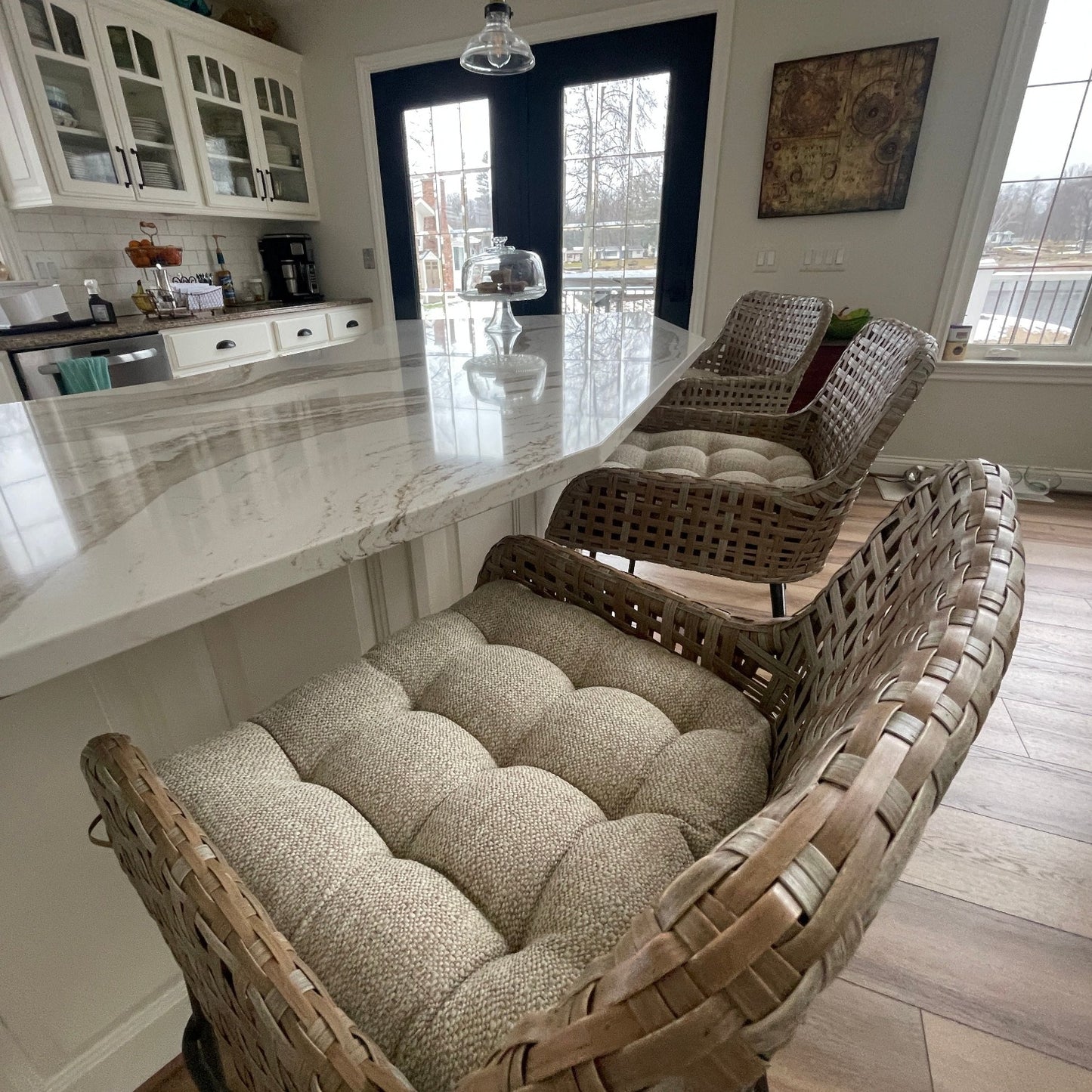 neutral colored wicker chair cushions in a cream upholstery fabric with a tweed texture on bar chairs at the kitchen island