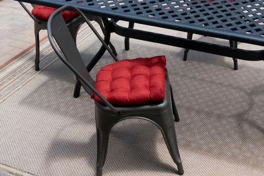 red tolix chair cushion on a metal chair at an outdoor dining table on the patio