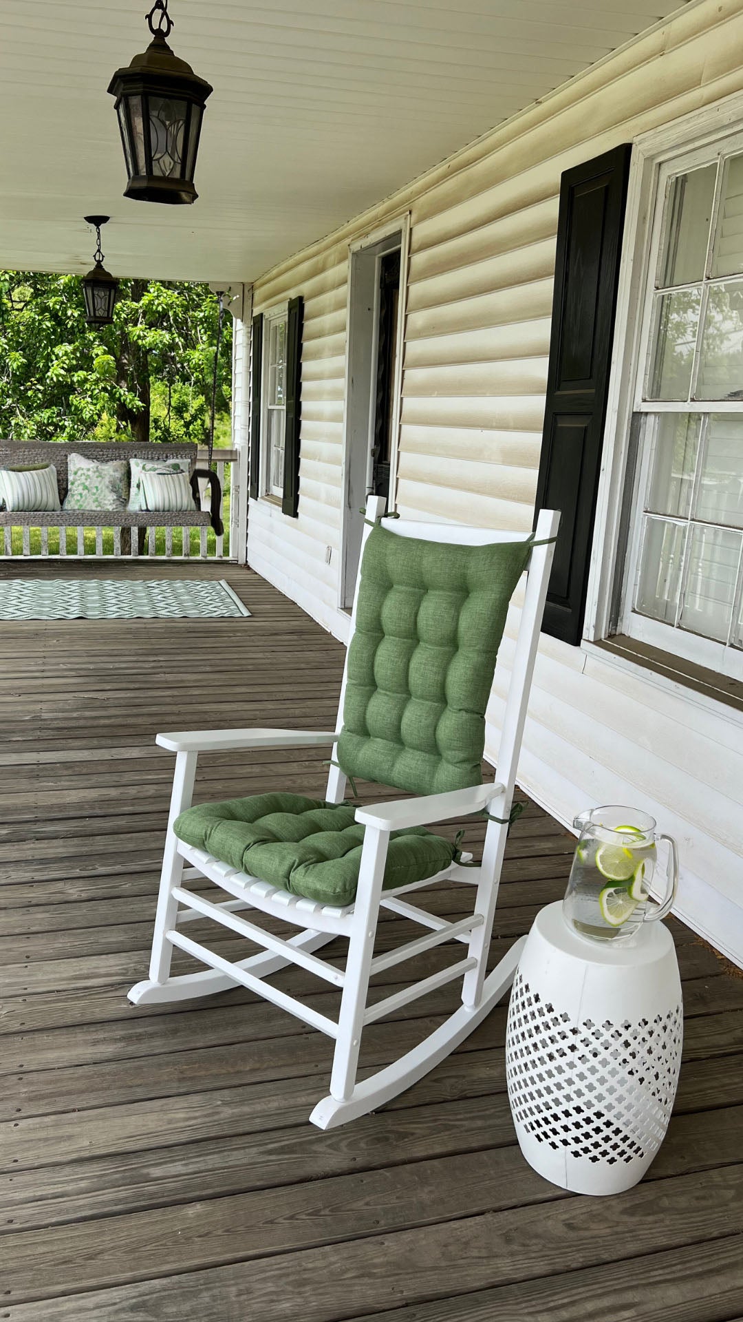 green outdoor rocking chair cushions on a white rocker with a porch swing and green pillows