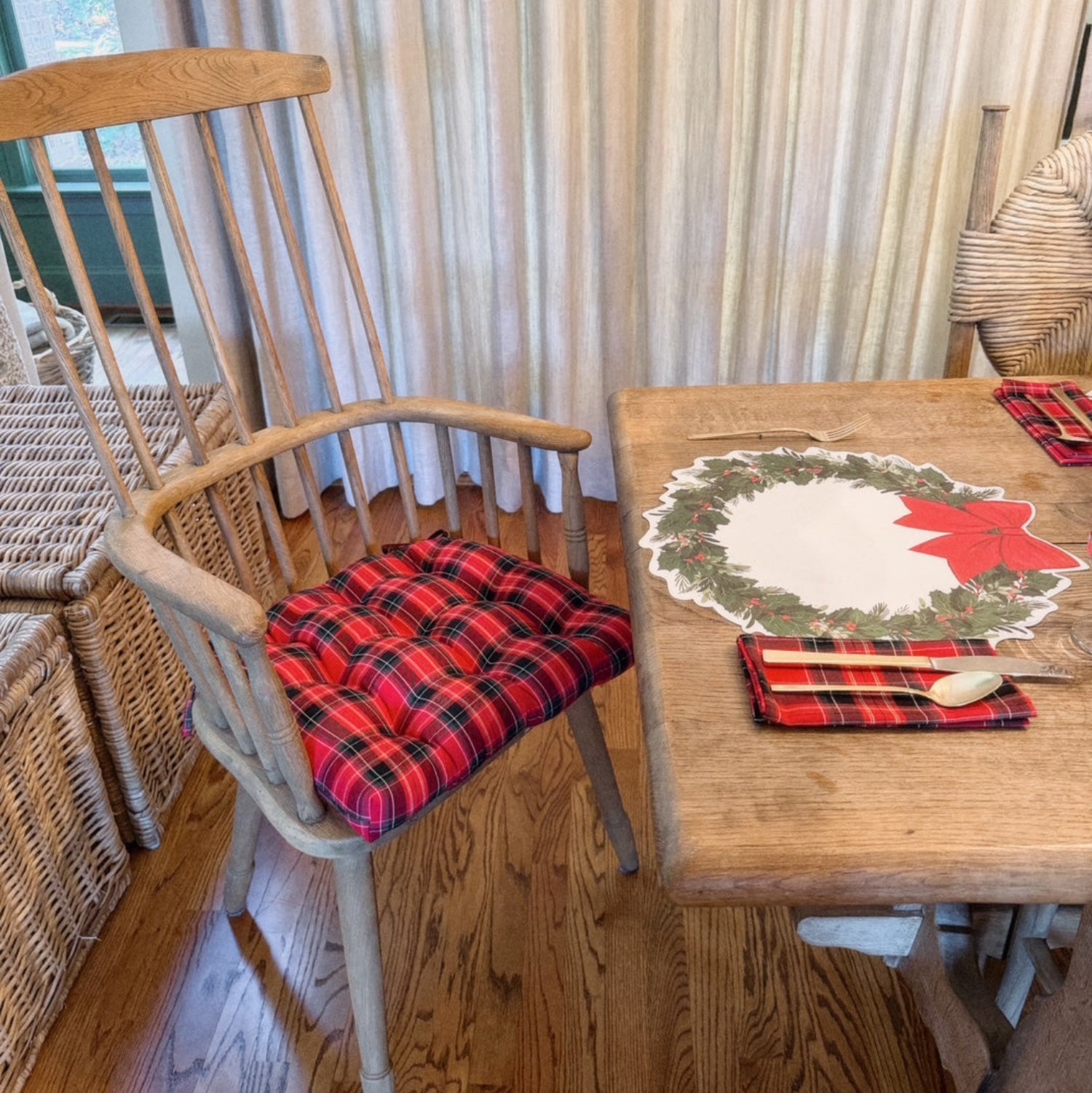 Dining room with wooden chair and table set for Christmas, featuring plaid cushions and placemats.