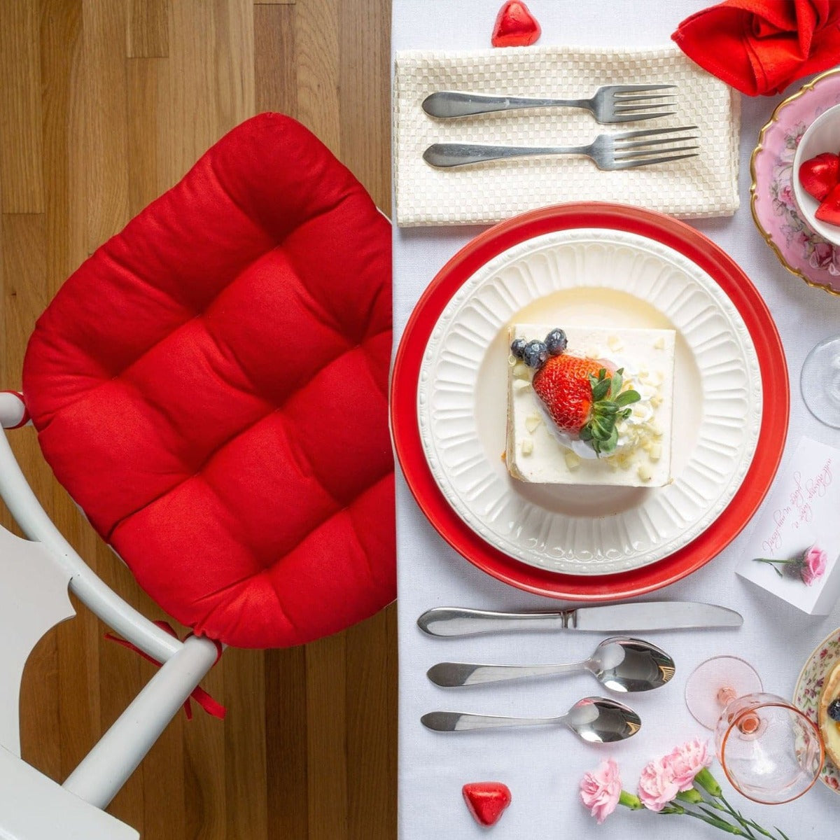 ruby red chair pads on vintage white dining chairs at dining room table set for valentines party