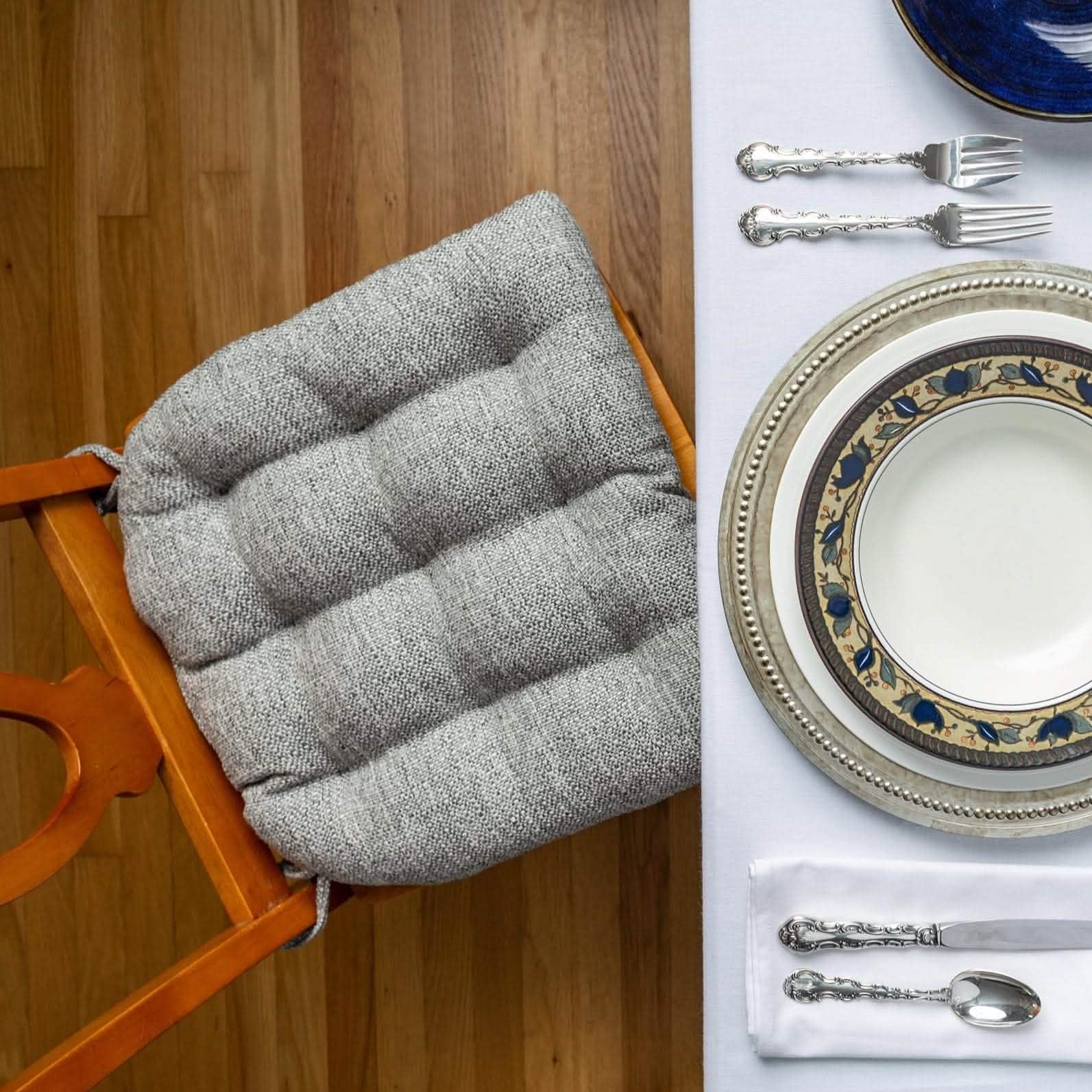 Silver colored dining chair pad in formal dining room with pewter charger plate