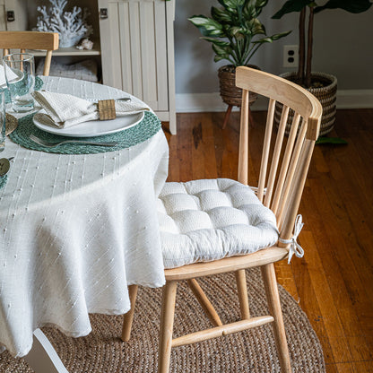 neutral colored basket weave pattern dining chair cushions with ties on natural wood dining chairs at coastal dining table