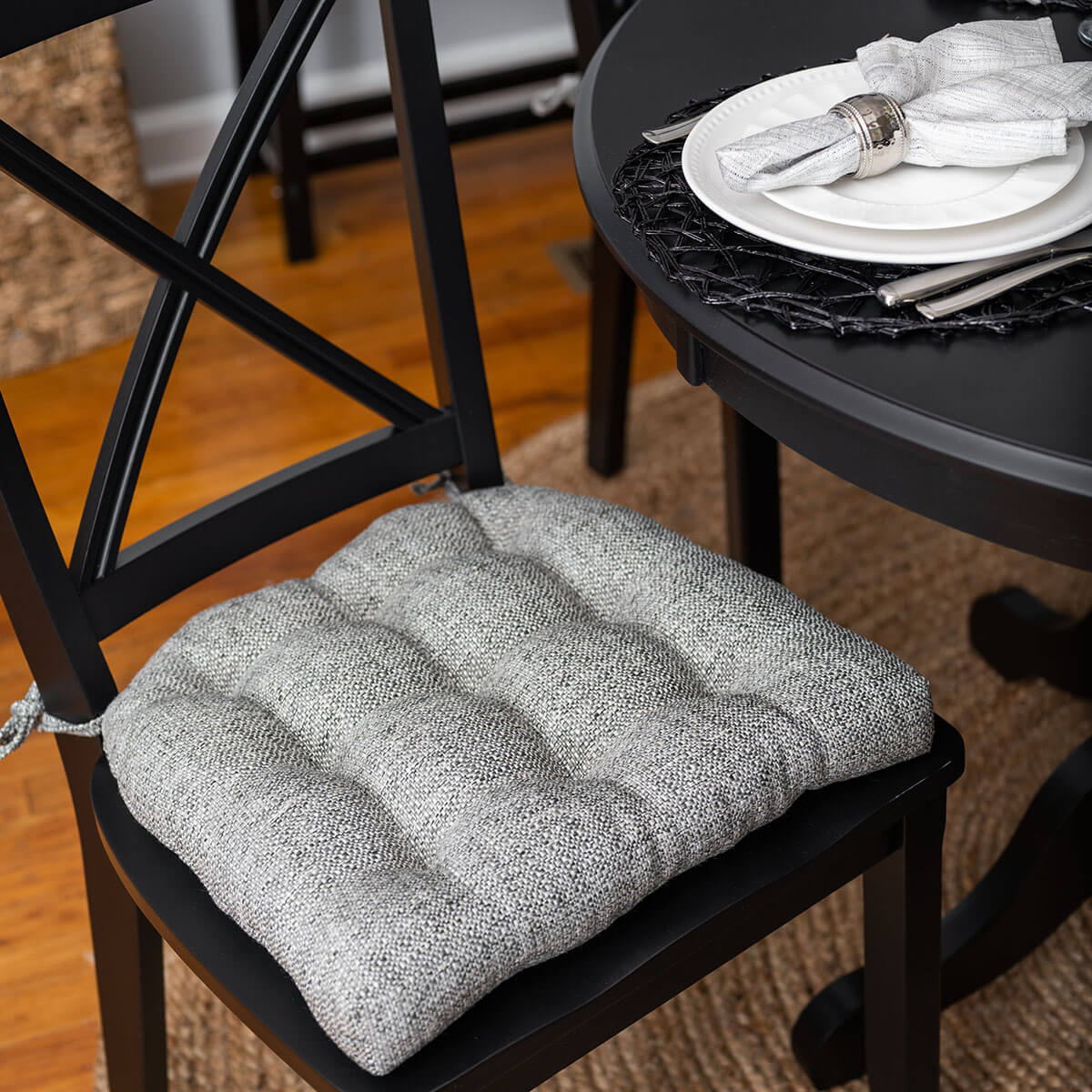 grey upholstered dining chair cushion at black dining room set for dinner party with silver place settings