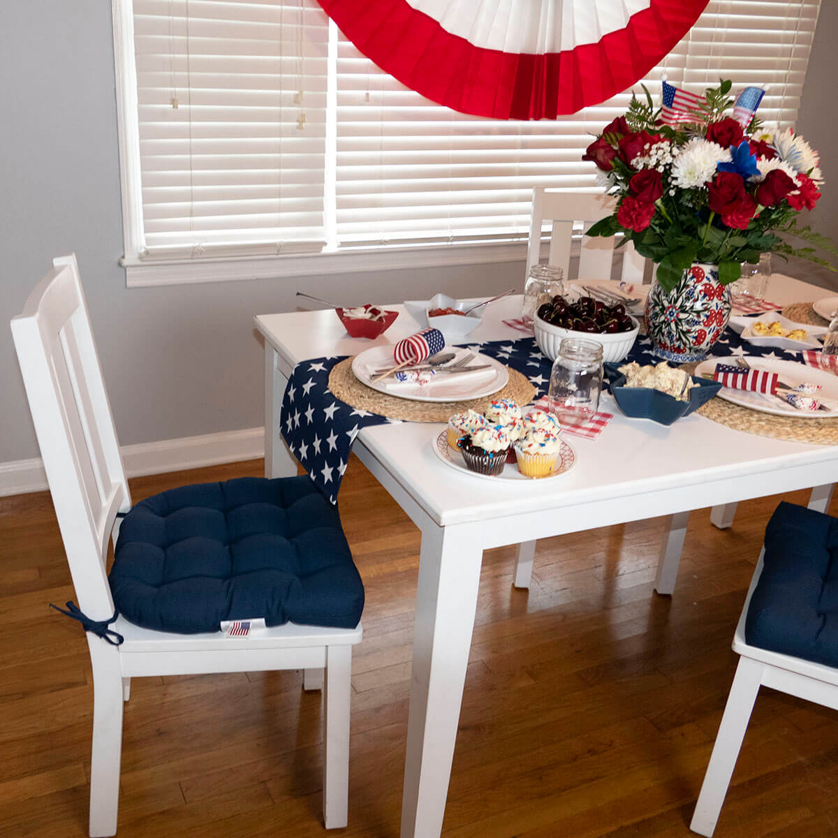 navy blue dining room chair pads on white wood dining chairs at farmhouse table set for 4th of july bbq