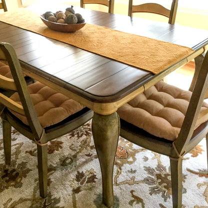 earth tones dining room with rust colored chair pads on green dining chairs with camel colored table runner and acorn decor on dining room table