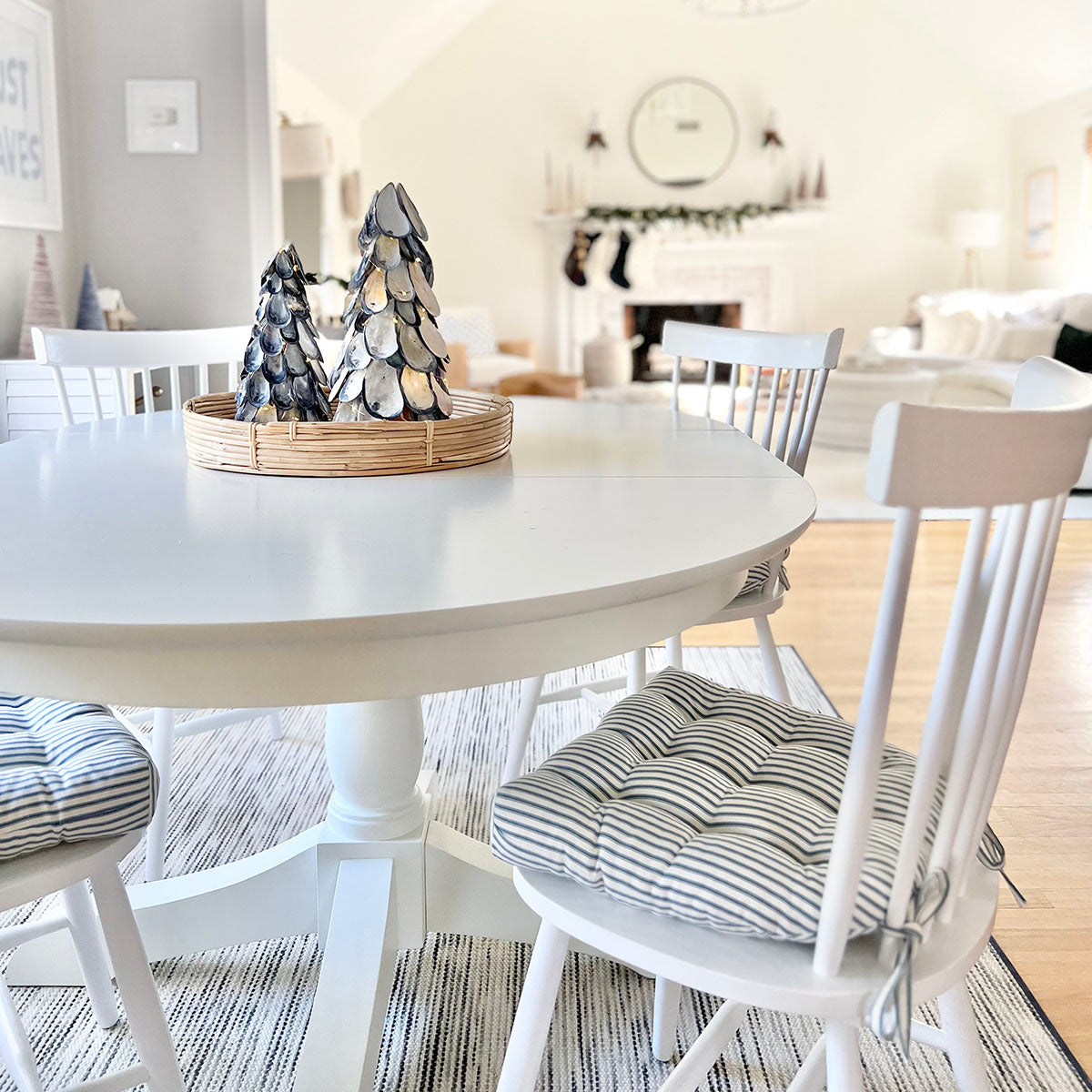 coastal christmas theme dining room with navy blue ticking stripe chair pads on white dining chairs at farmhouse kitchen table